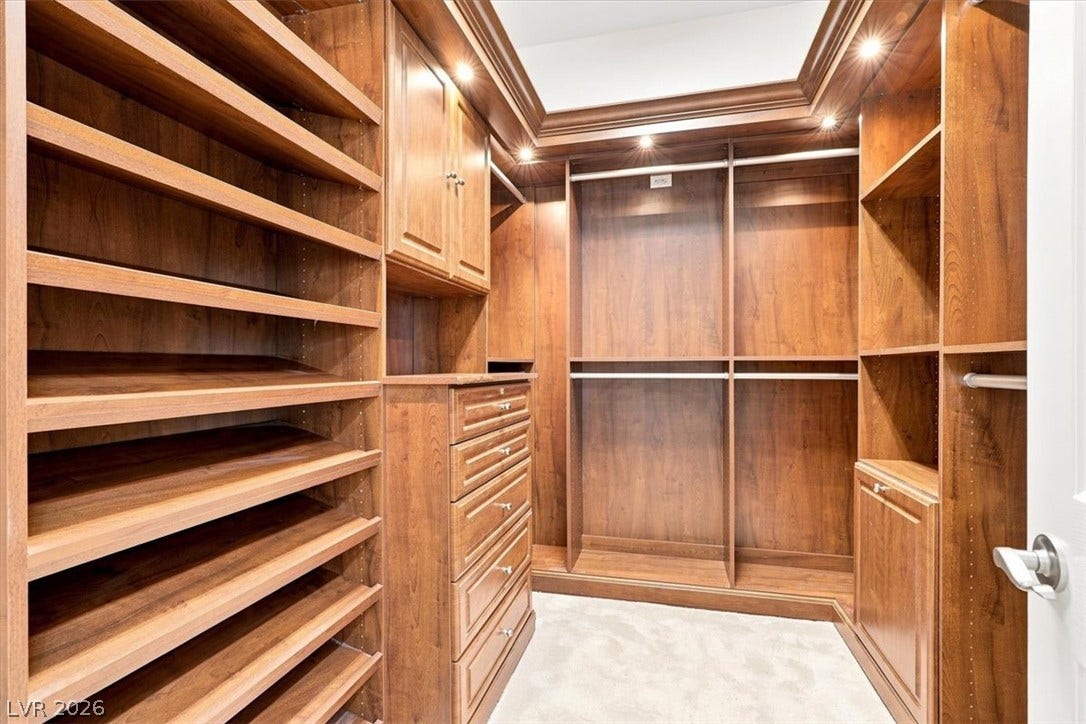 Rich wood built-ins and soft carpeting define this organized closet space.