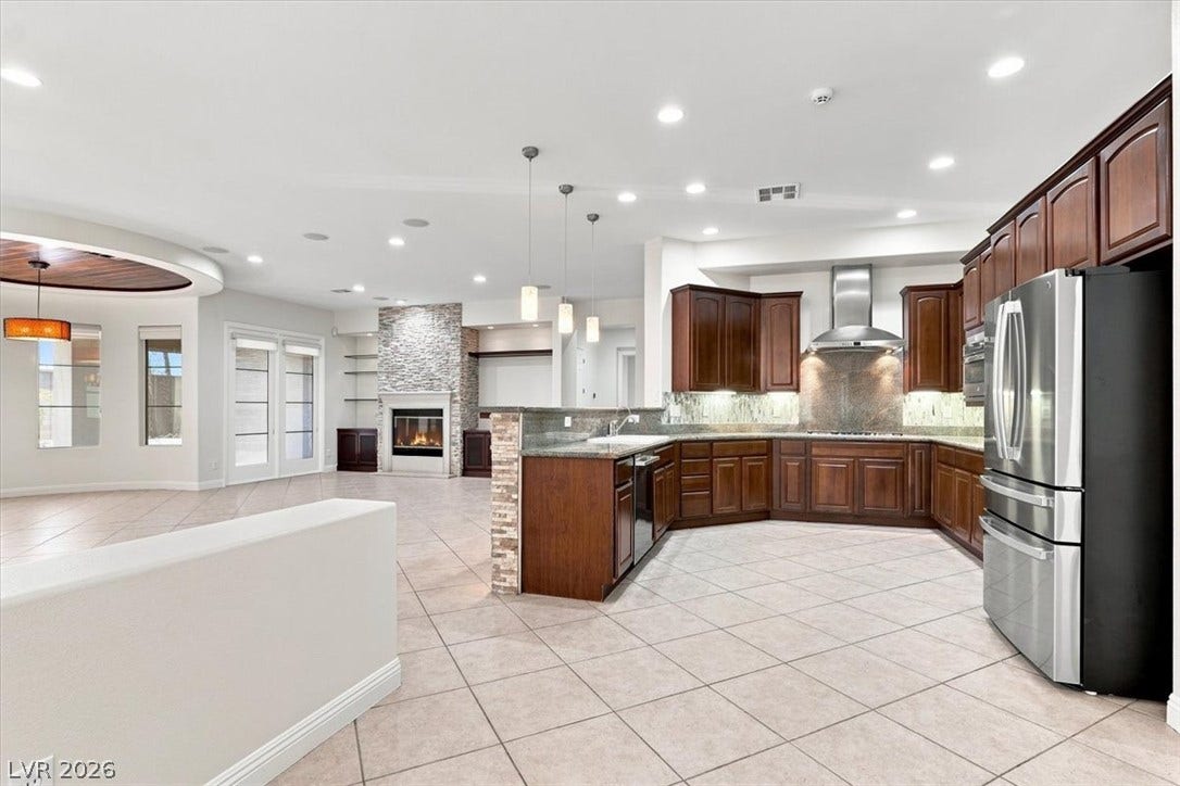 Rich wood cabinetry and tile flooring flow seamlessly throughout this open-concept culinary space.