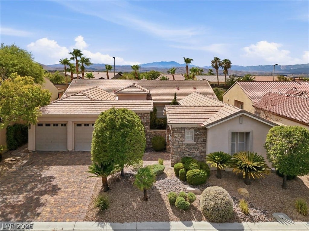 Desert landscaping and stone accents frame this classic tile-roof residence with a spacious driveway.