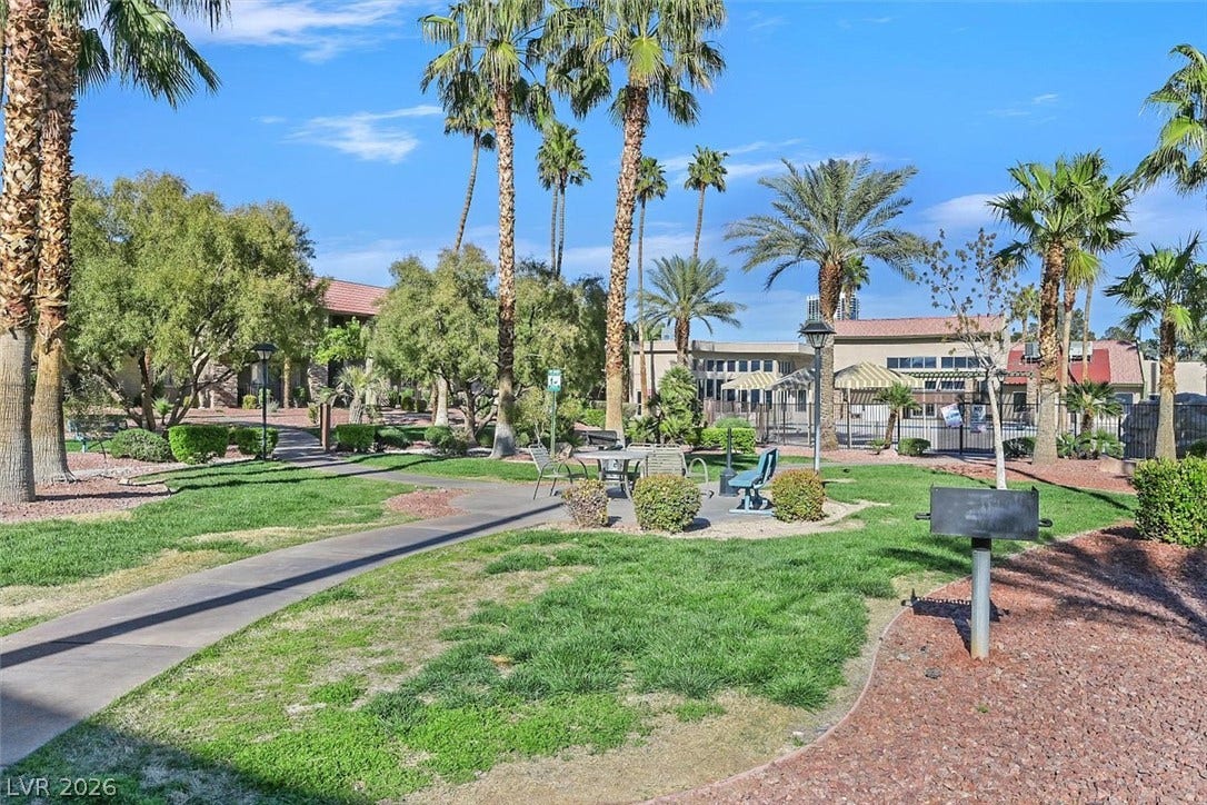 5081 River Glen Drive, #97, Las Vegas, NV 89103 Paved walkways wind through a grassy park area shaded by mature palm trees.