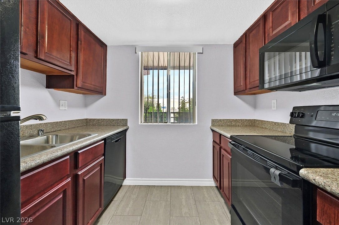 5081 River Glen Drive, #97, Las Vegas, NV 89103 Rich wood cabinetry pairs with durable stone counters in this functional galley layout.