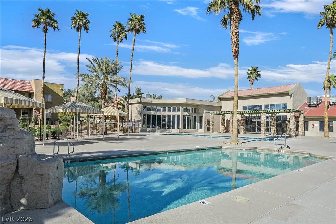 5081 River Glen Drive, #97, Las Vegas, NV 89103 Towering palm trees frame a sparkling community swimming pool under blue desert skies.