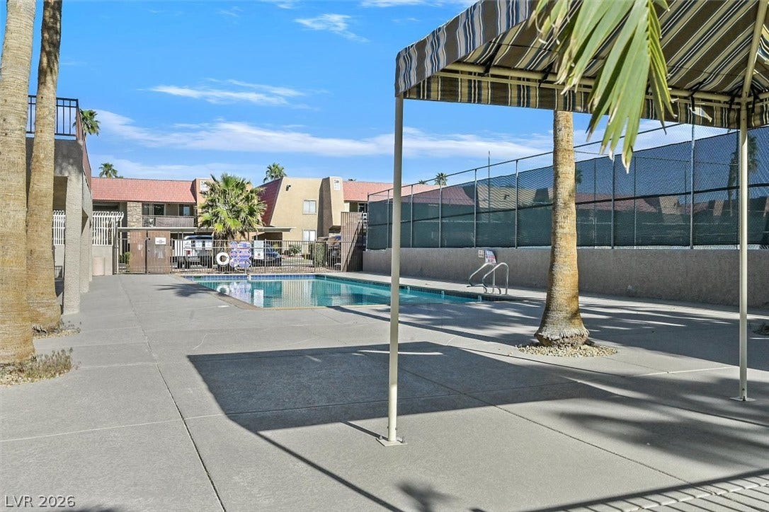 5081 River Glen Drive, #97, Las Vegas, NV 89103 Palm trees surround a clear swimming pool with concrete decking under a bright blue sky.