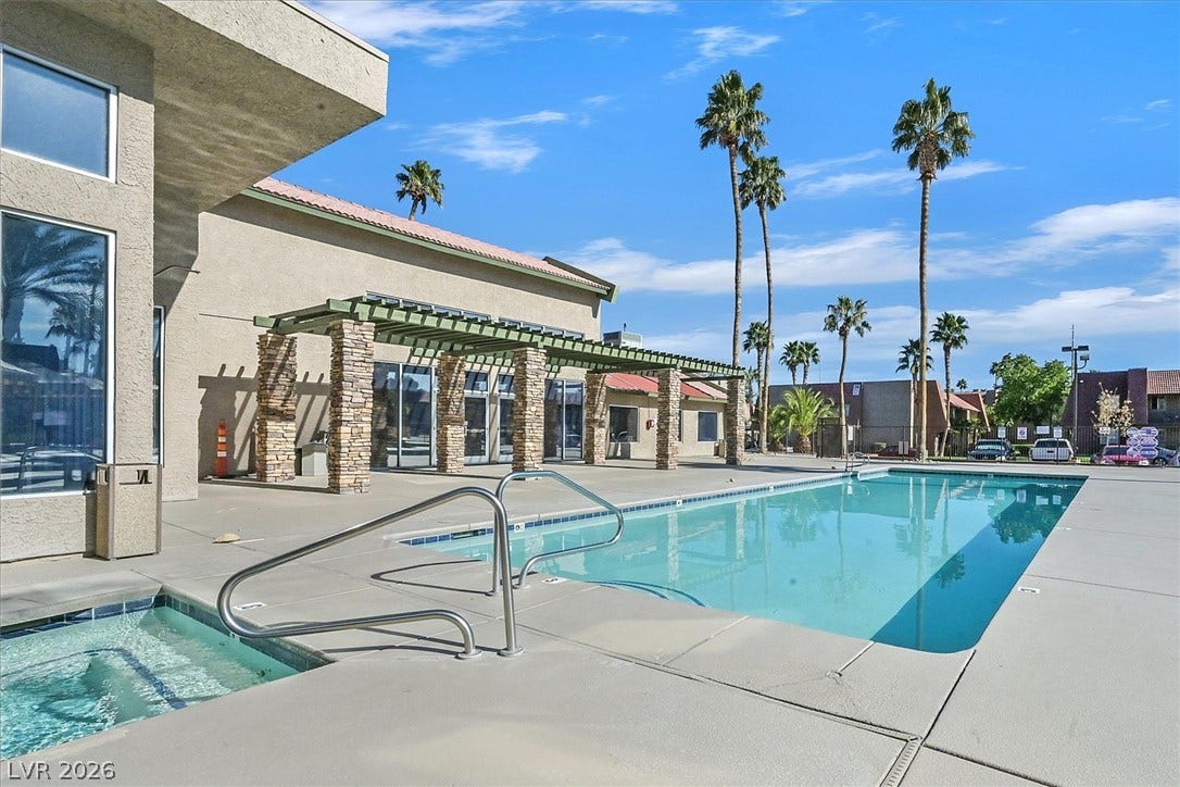5081 River Glen Drive, #97, Las Vegas, NV 89103 A sparkling swimming pool and integrated spa sit adjacent to a stone-pillar pergola structure.