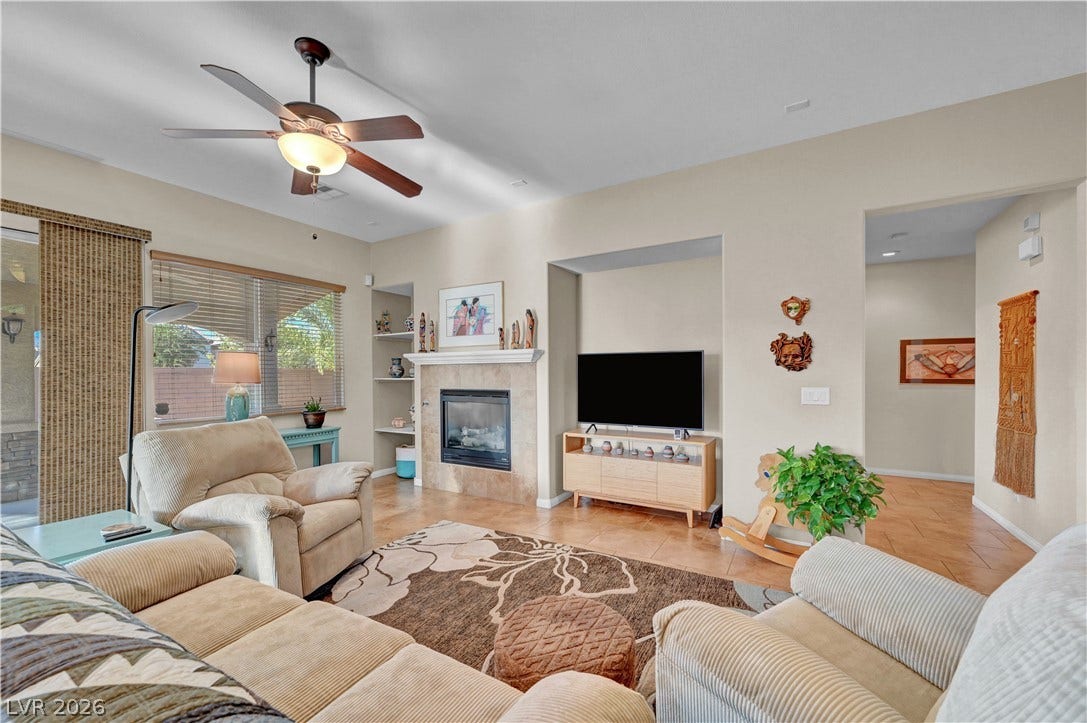 9928 Tradition Creek Avenue, Las Vegas, NV 89149 A comforting living space features a fireplace and a cooling ceiling fan for year-round enjoyment.