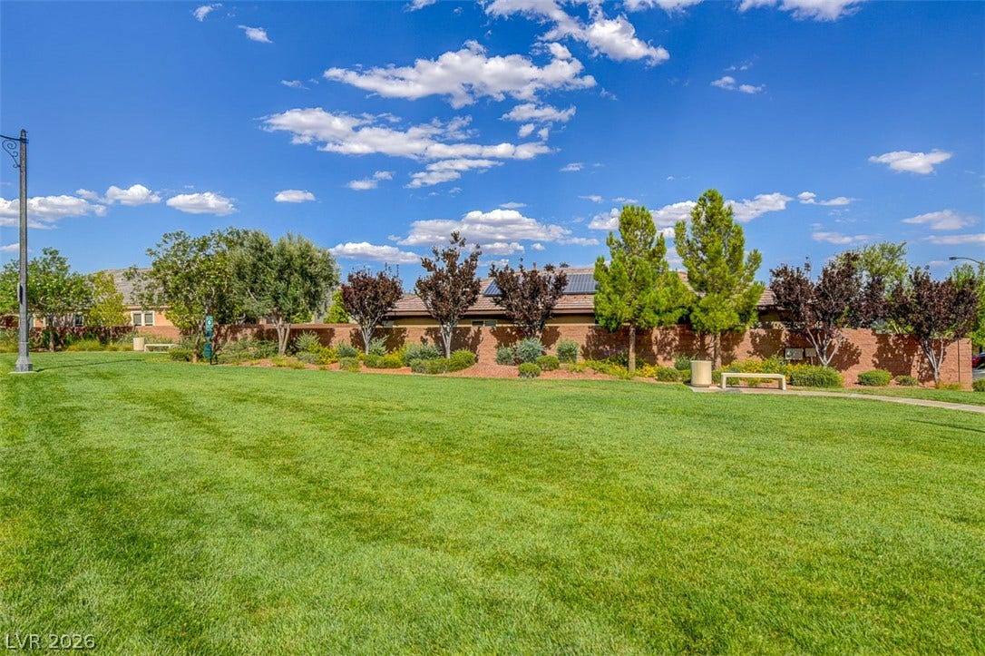 9928 Tradition Creek Avenue, Las Vegas, NV 89149 A verdant park with a mature brick wall and flourishing landscaping offers a serene community setting.