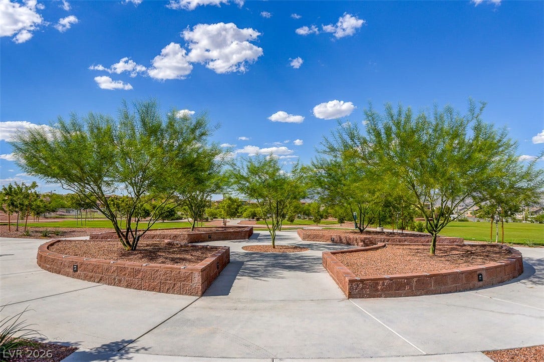 9928 Tradition Creek Avenue, Las Vegas, NV 89149 A well-maintained park area features mature trees set in raised brick planters, offering serene community green space.