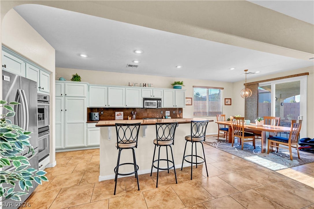 9928 Tradition Creek Avenue, Las Vegas, NV 89149 A well-lit kitchen with a breakfast bar seamlessly connects to the dining area and outdoor access.