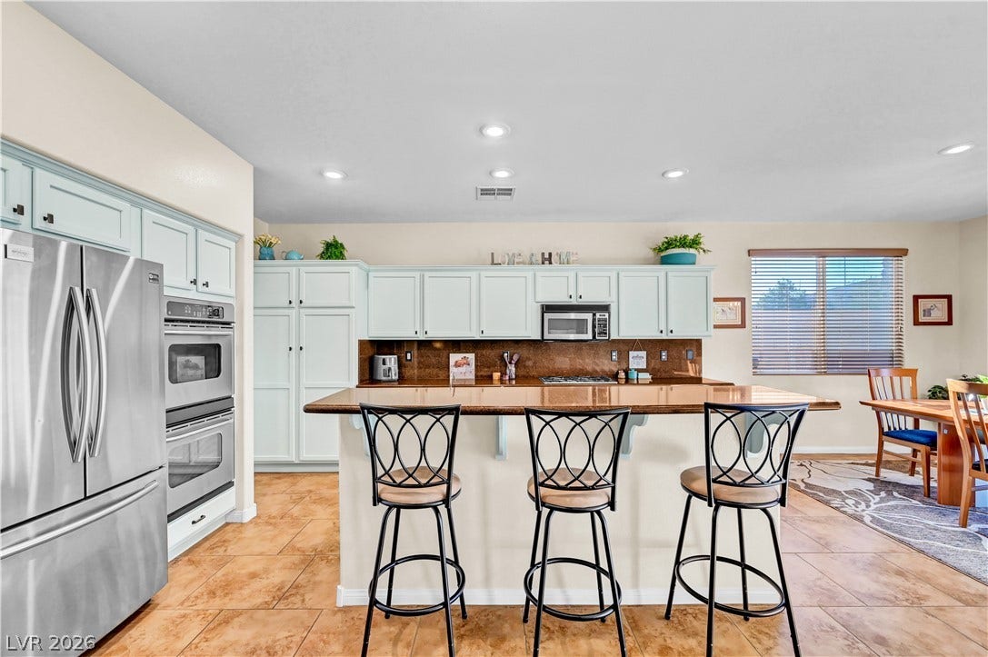 9928 Tradition Creek Avenue, Las Vegas, NV 89149 A well-appointed kitchen features ample counter space, light cabinetry, and an inviting breakfast bar.