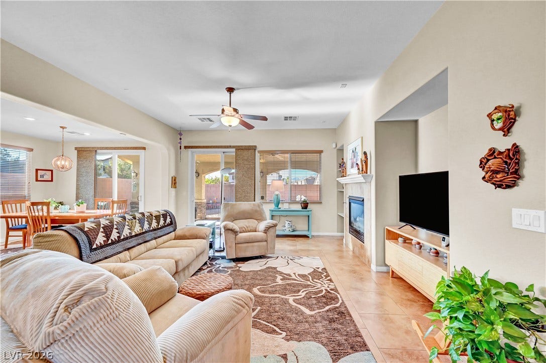 9928 Tradition Creek Avenue, Las Vegas, NV 89149 A well-lit living area with tile flooring seamlessly connects to a dining space and outdoor patio.