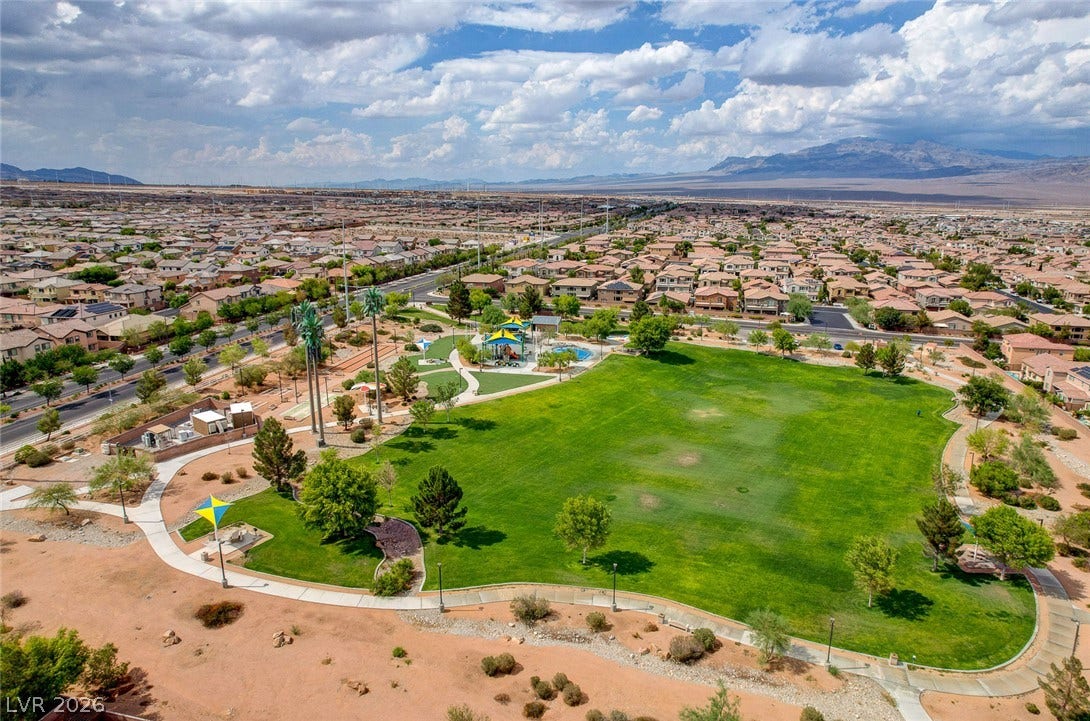 9928 Tradition Creek Avenue, Las Vegas, NV 89149 An aerial perspective reveals a vibrant community park with extensive green space, a playground, and winding paths, all framed by residential rooftops.