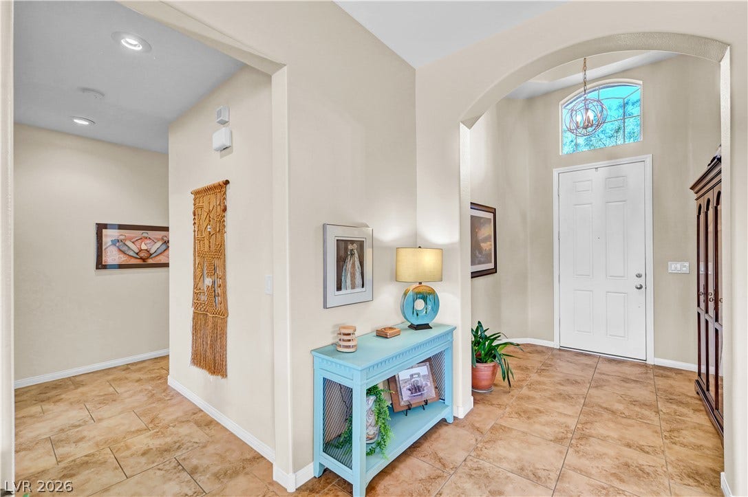 9928 Tradition Creek Avenue, Las Vegas, NV 89149 Step inside this inviting entry, offering a warm welcome with tile flooring and an elegant arched doorway leading to an interior hallway.