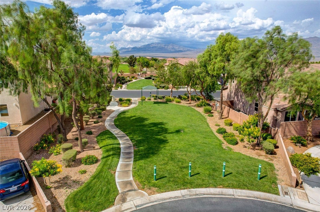 9928 Tradition Creek Avenue, Las Vegas, NV 89149 A winding path through verdant lawns leads to a community green space, framed by mature trees and mountain views.