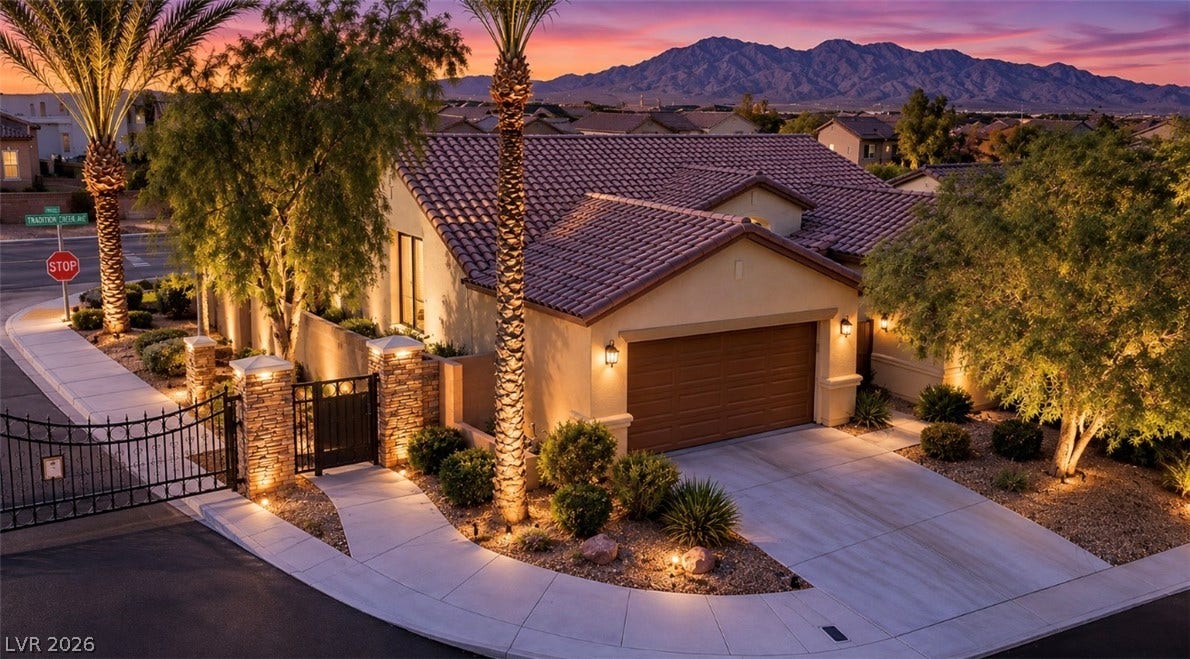 9928 Tradition Creek Avenue, Las Vegas, NV 89149 Curb appeal flourishes with a gated stone entrance, inviting walkway, and meticulously illuminated landscaping.