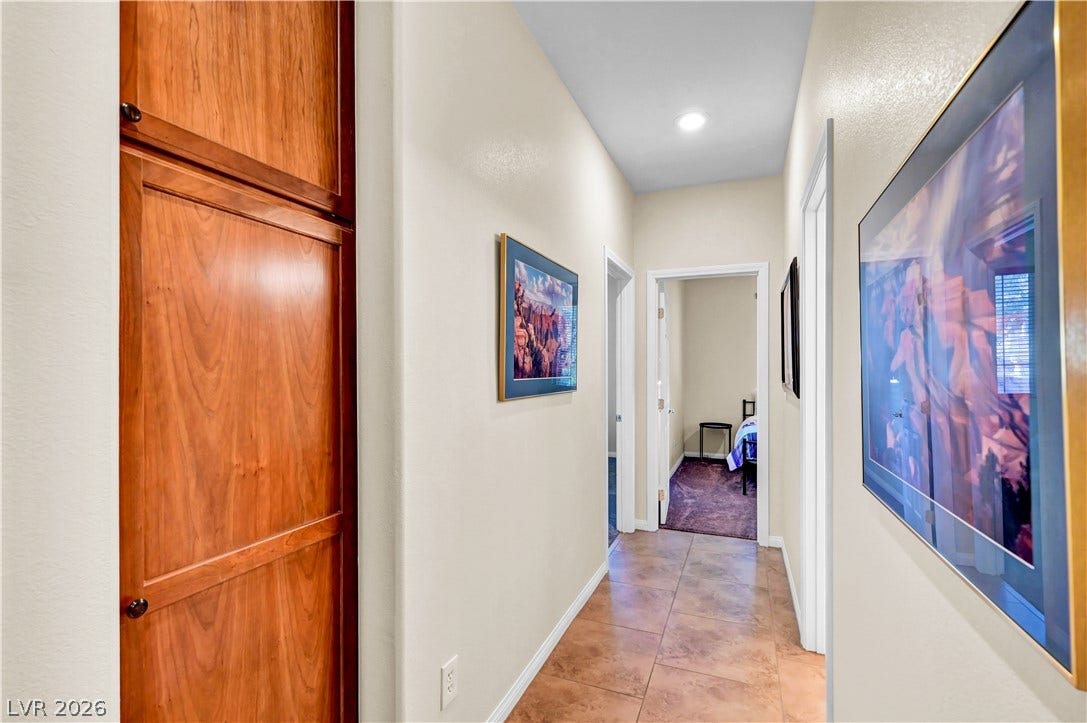 9928 Tradition Creek Avenue, Las Vegas, NV 89149 A well-lit corridor with warm tile flooring connects the living spaces, featuring a recessed wooden built-in cabinet.