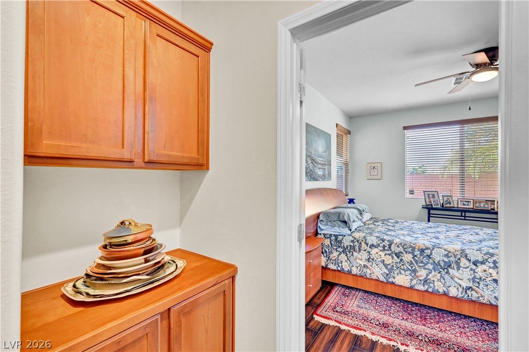 9928 Tradition Creek Avenue, Las Vegas, NV 89149 A tranquil bedroom retreat awaits, featuring rich wood flooring and a refreshing ceiling fan.