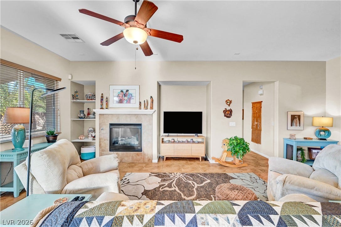 9928 Tradition Creek Avenue, Las Vegas, NV 89149 A welcoming living area offers a cozy fireplace and a ceiling fan, perfect for year-round comfort.