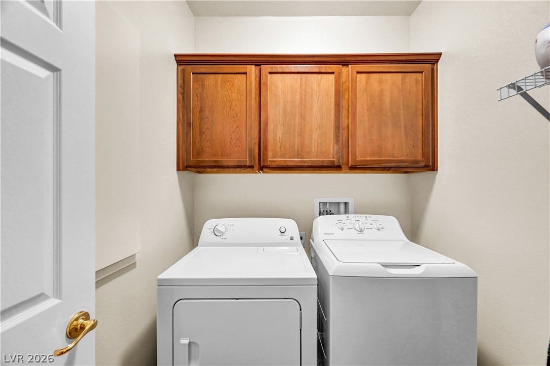 9928 Tradition Creek Avenue, Las Vegas, NV 89149 Functional laundry room featuring warm wood cabinetry and a convenient washer and dryer setup.