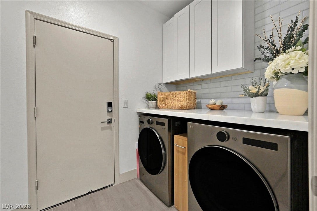 Functional laundry space featuring modern appliances beneath crisp white cabinetry.