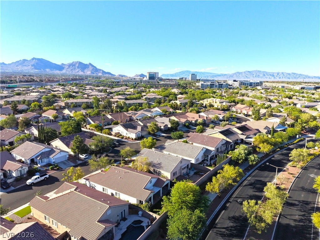 An aerial perspective reveals a sprawling residential community nestled against a majestic mountain backdrop.