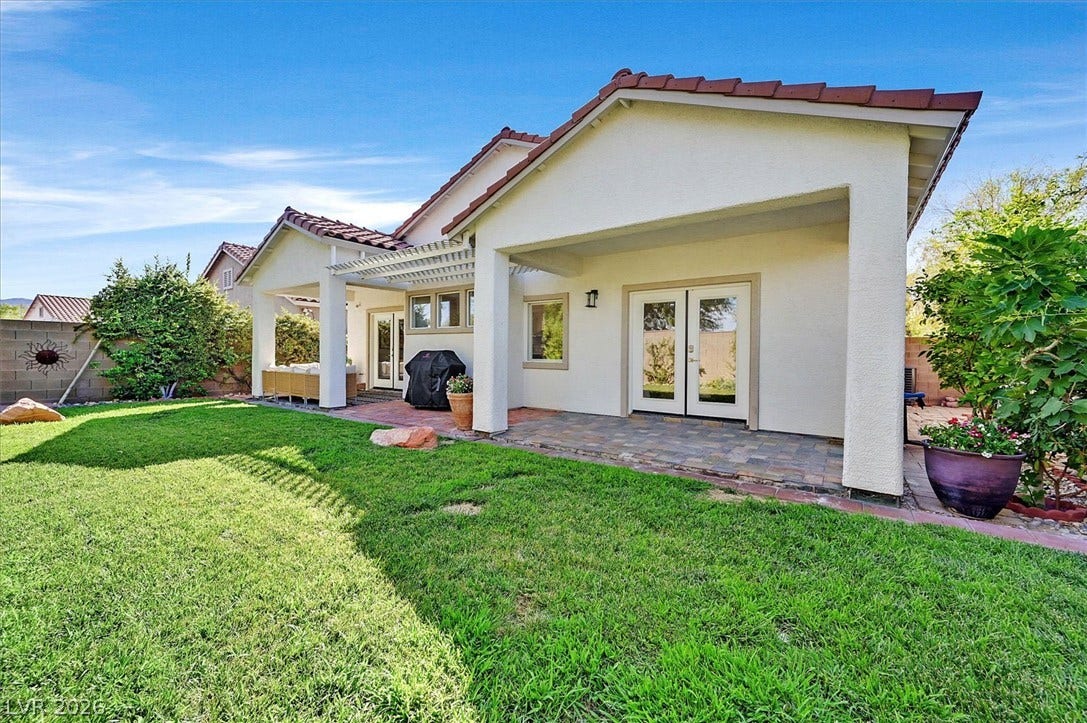 A verdant backyard retreat offers a spacious lawn and a covered patio perfect for outdoor living.