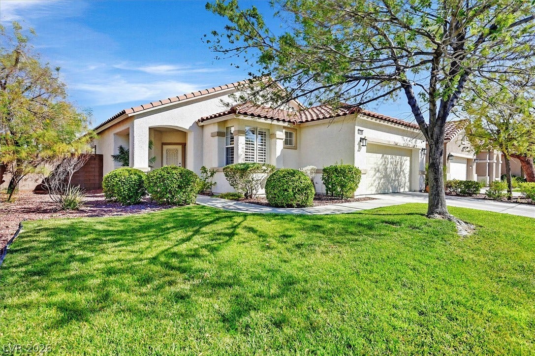 A well-maintained lawn welcomes you to this residence, featuring a two-car garage and a tile roof.