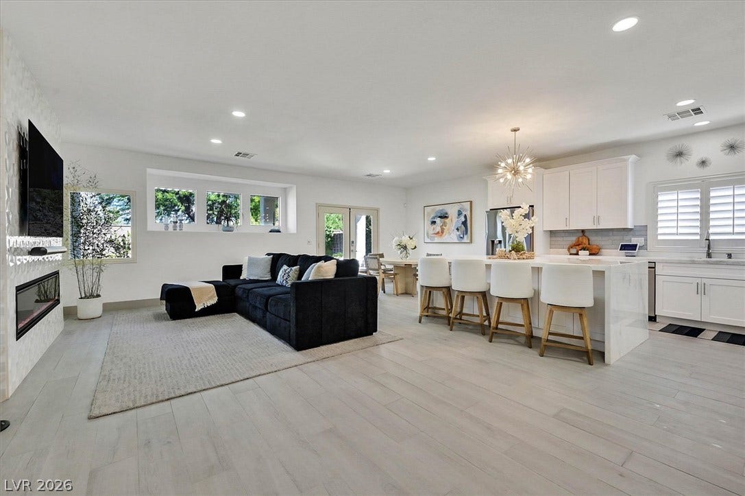 An open-concept living area features light porcelain flooring and a contemporary kitchen island with seating.