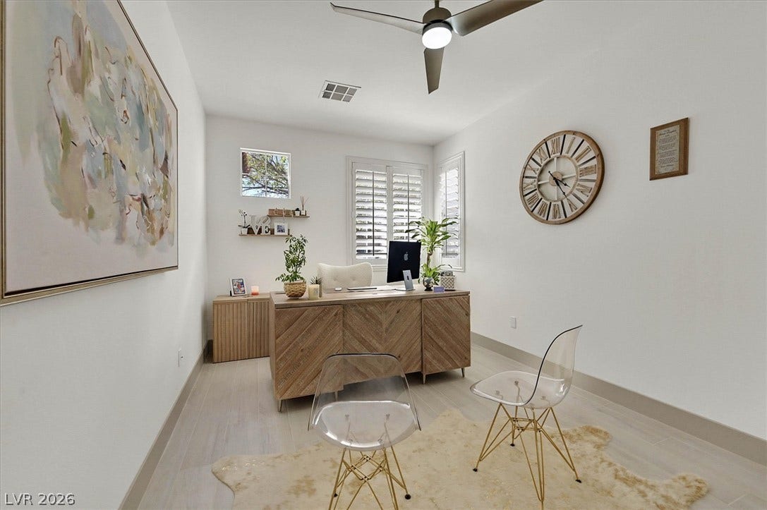 An inviting office with features a modern wood desk, framed windows, and a sleek ceiling fan for comfortable productivity.