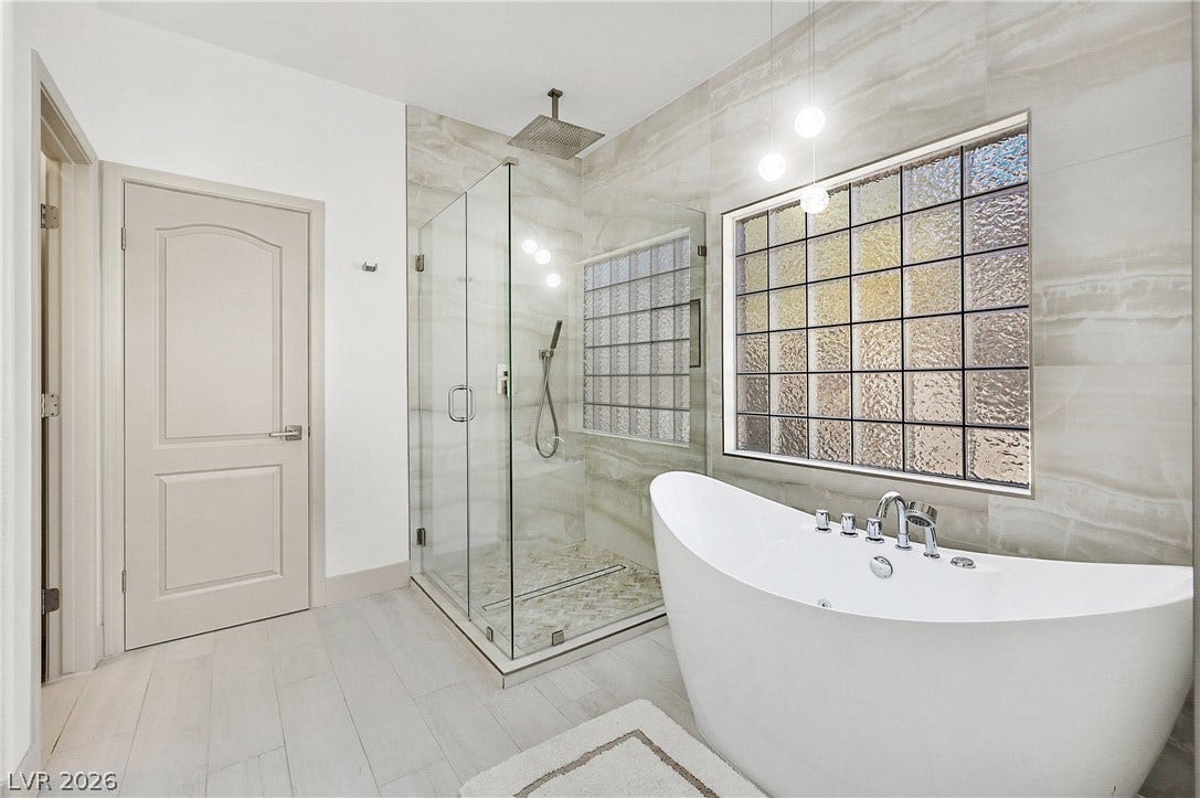 Luxurious spa-like bath features a glass-enclosed shower and a freestanding soaking tub for ultimate relaxation.
