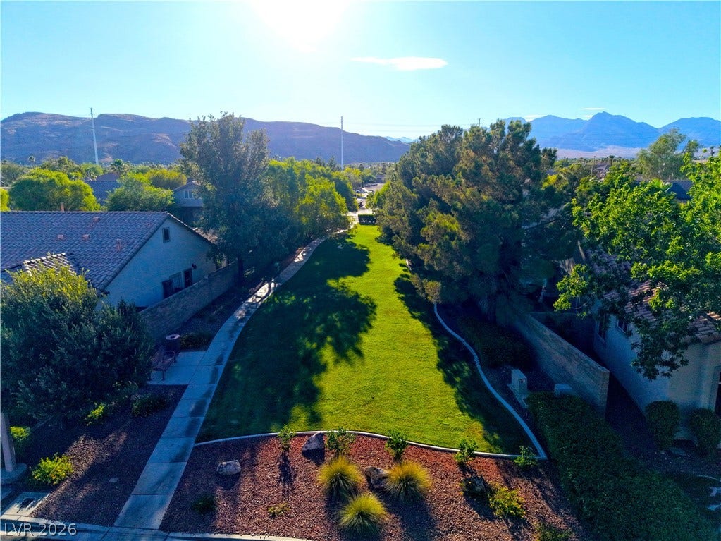A verdant community greenbelt with mature trees, nestled between homes, offers a serene outdoor space.