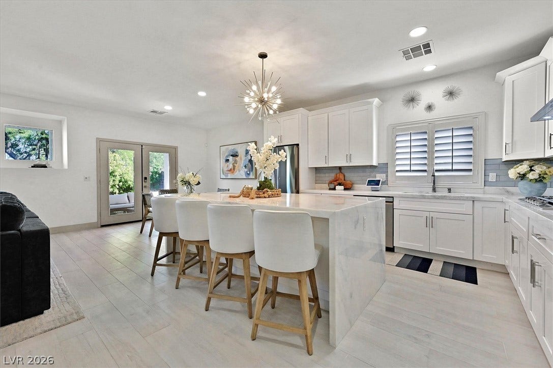 A well-appointed kitchen features a grand island with water-fall with seating and sophisticated appliances.