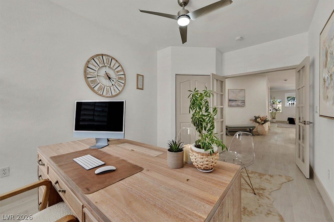 A dedicated home office space features bright lighting and elegant double French doors opening to the hallway.