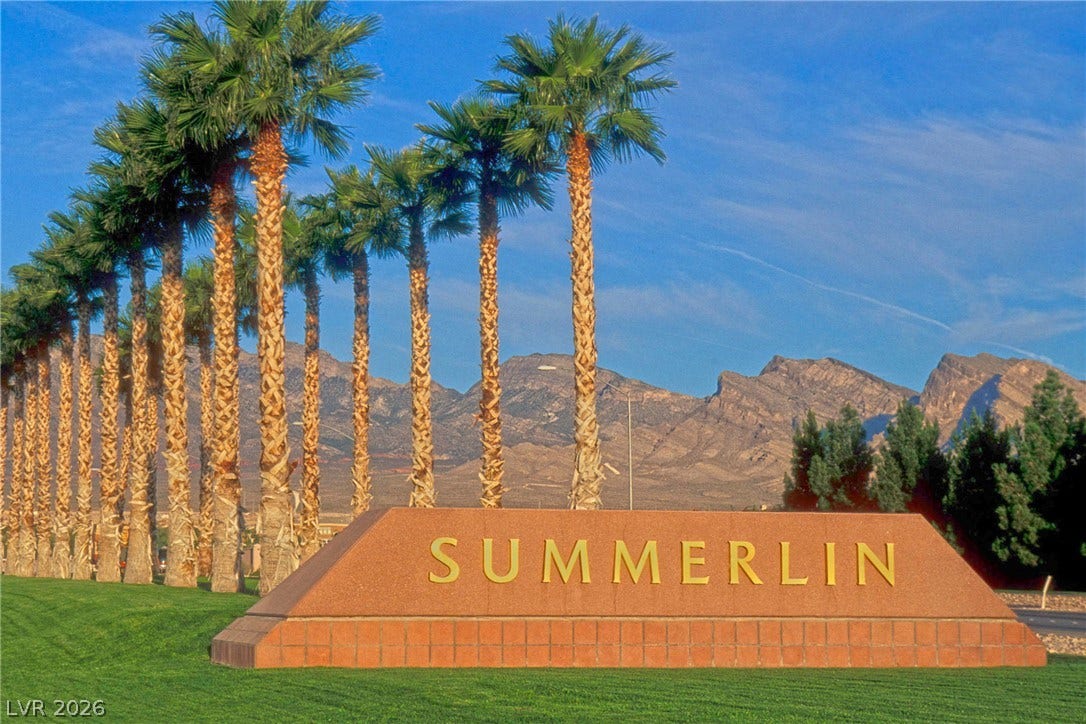 An inviting entrance with a meticulously maintained lawn, framed by a line of mature palm trees and rugged mountain views.