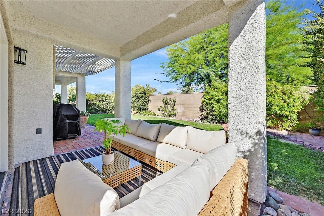 A spacious covered patio invites relaxation with comfortable outdoor seating and views of the verdant private yard.