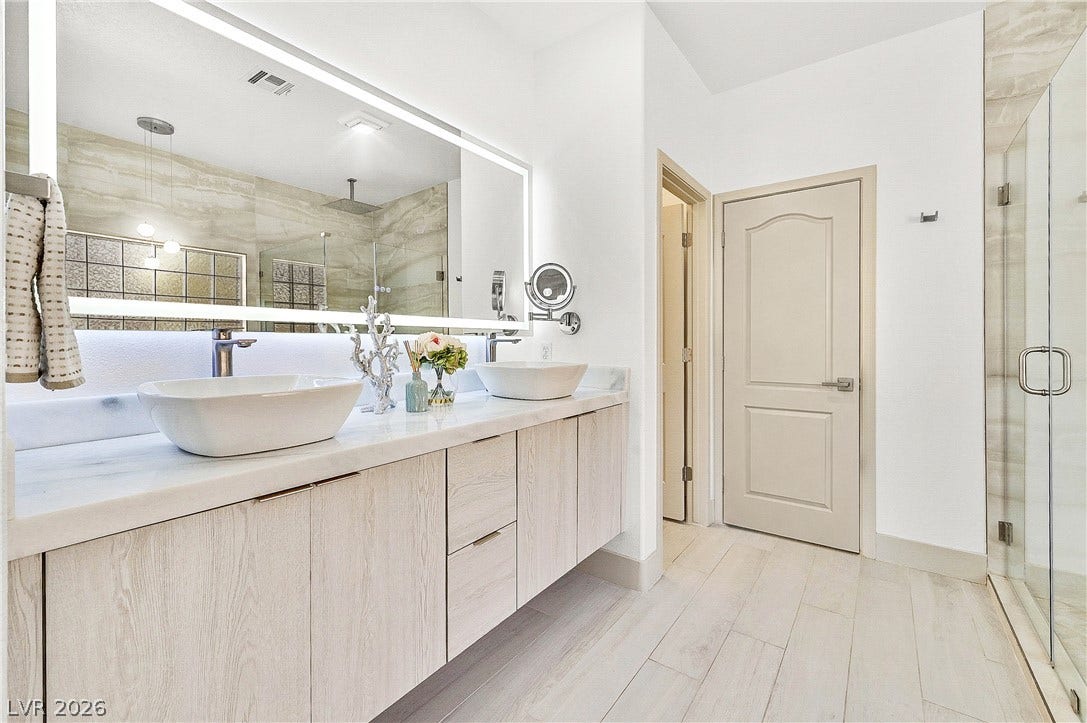 Modern double vanity with vessel sinks and illuminated mirrors elevate this chic bathroom.