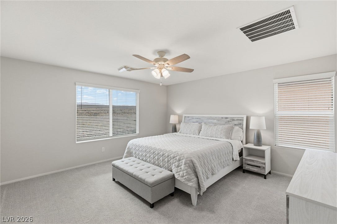 A naturally illuminated bedroom offers comfort with soft carpeting and ample window light.