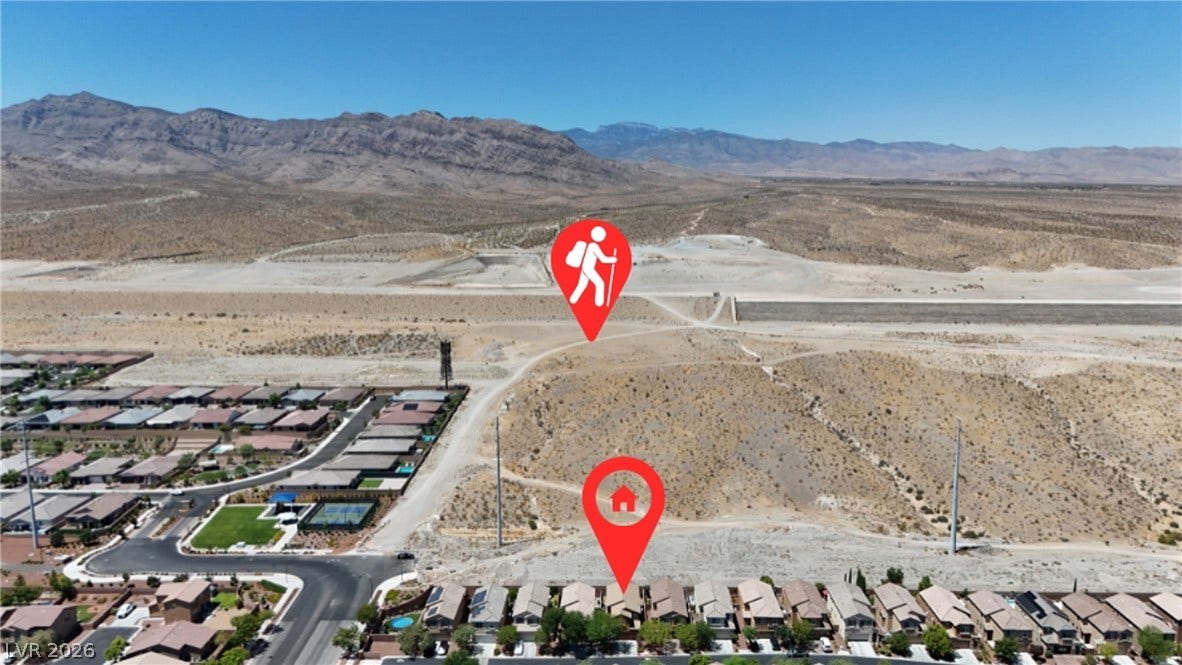A desert landscape with distant mountains, a community of homes, and an outdoor recreational area.