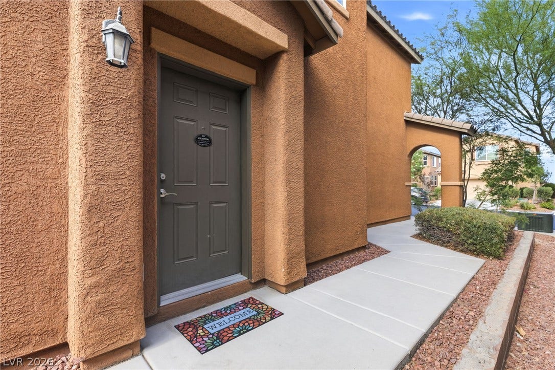 A welcoming entry invites you to this stucco residence, featuring a covered doorway and a structured walkway.