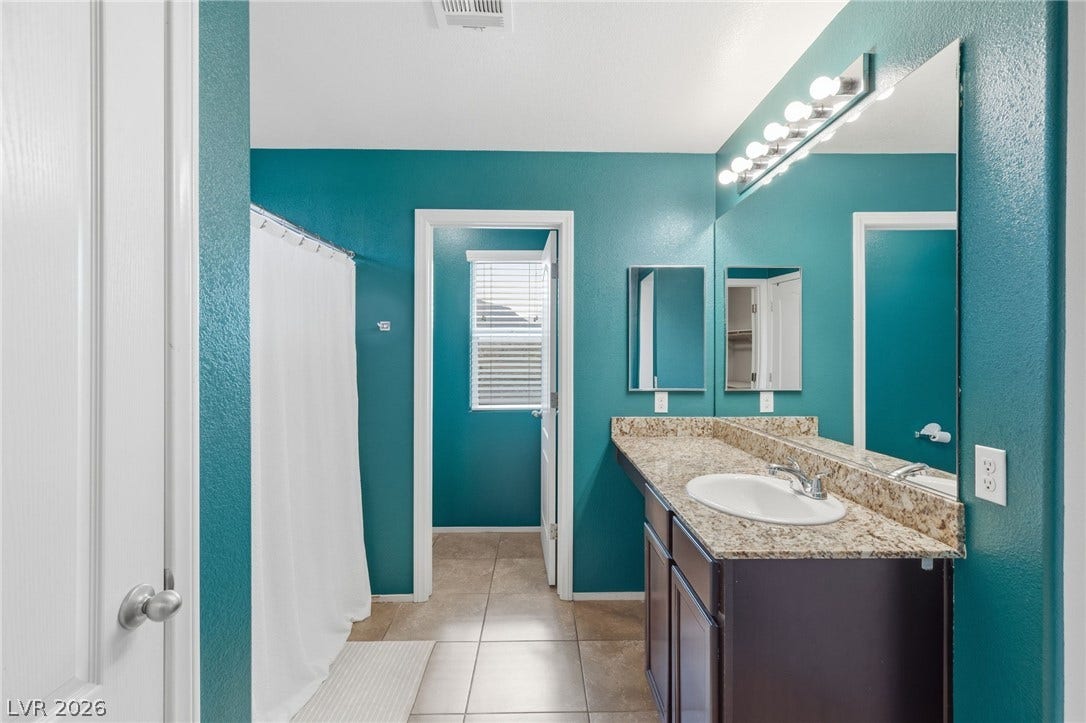A well-lit bathroom features a vanity with a sleek countertop and a shower area with privacy.