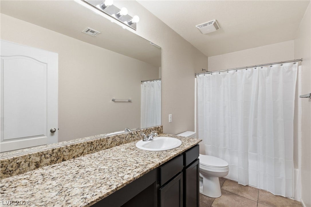 Well-appointed bath featuring a spacious granite vanity and a full shower with white curtain.