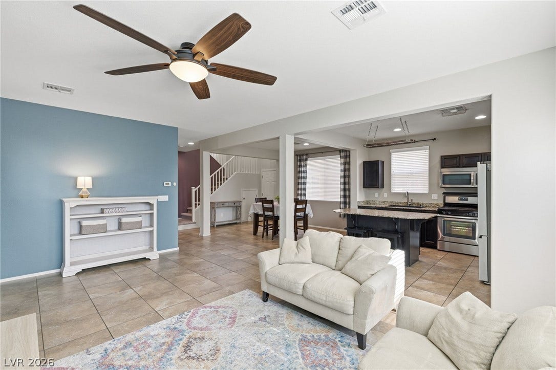 An inviting open-concept living area features a modern kitchen, dining space, and a comfortable lounging zone with tile flooring.