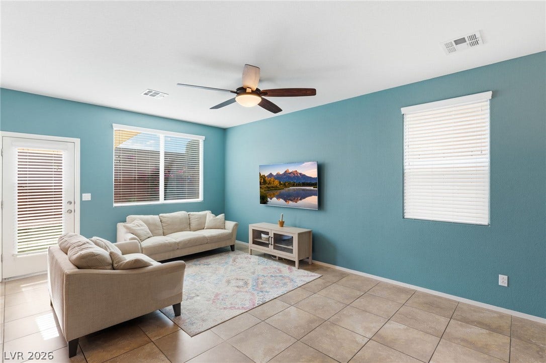 Natural light filters through the blinds, illuminating the tile flooring and ceiling fan.