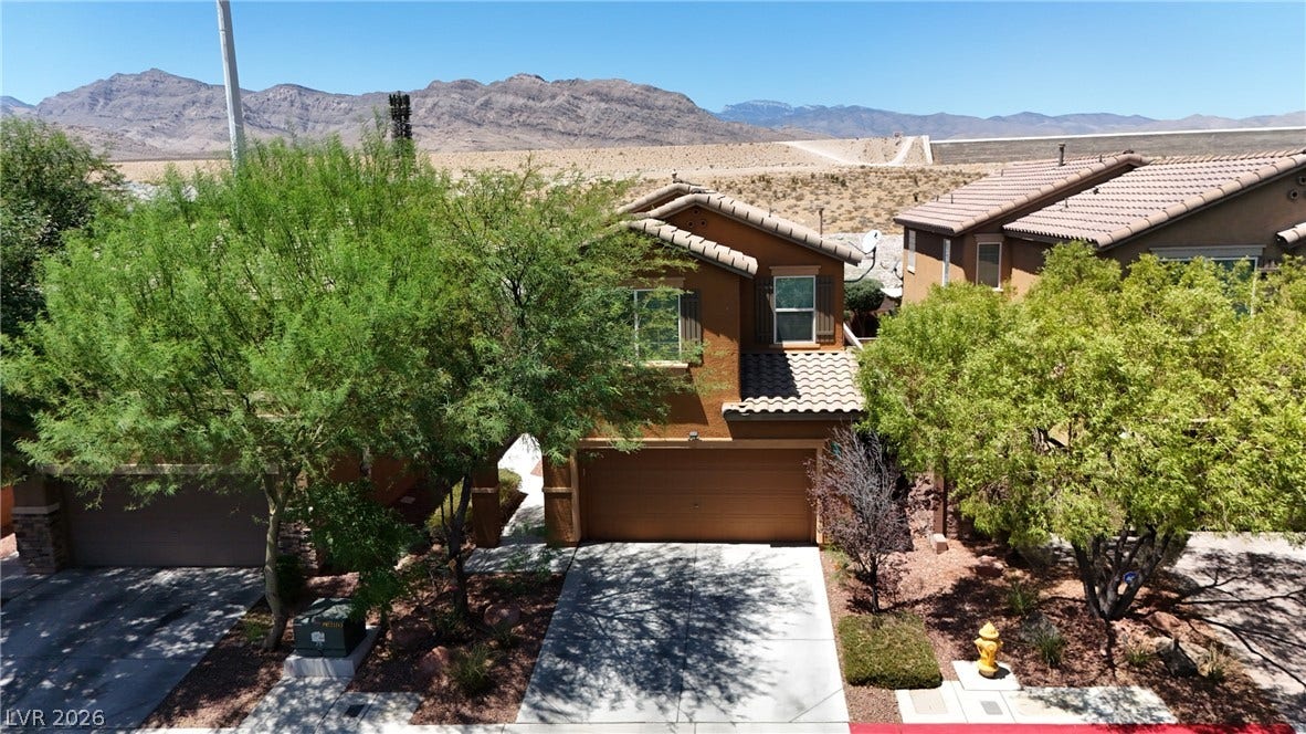 A well-maintained facade with desert landscaping offers a welcoming entry, backed by mountain views.