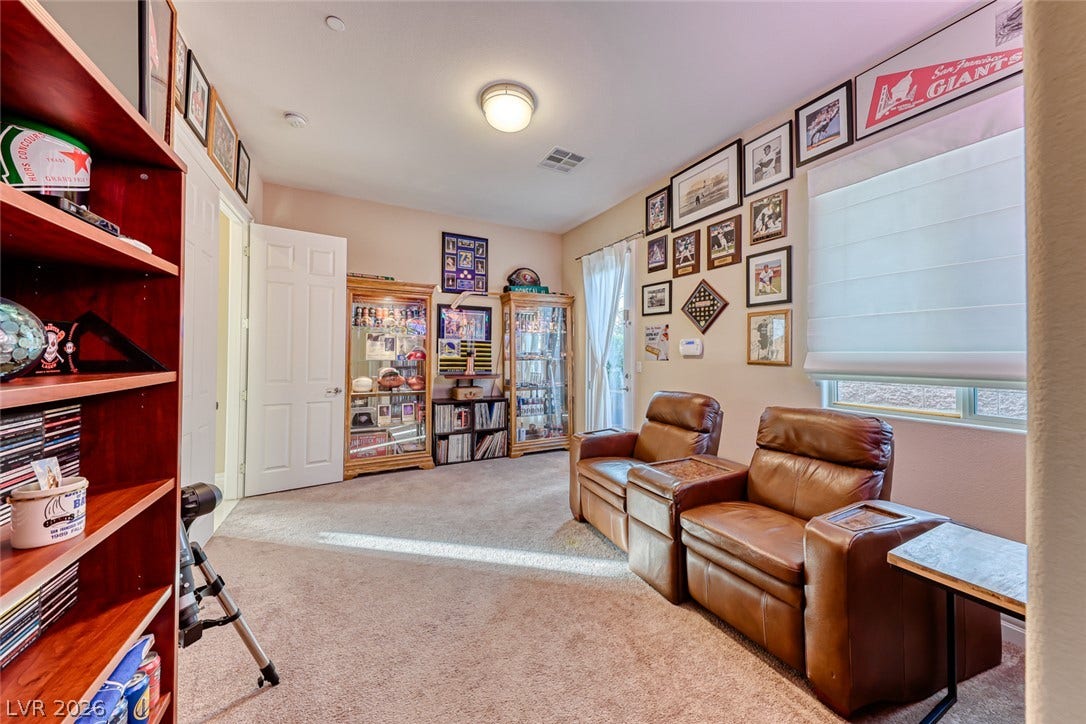 70 Portezza Drive, Henderson, NV 89011 An inviting room features comfortable seating, display cases, and ample shelving, offering a personalized retreat.