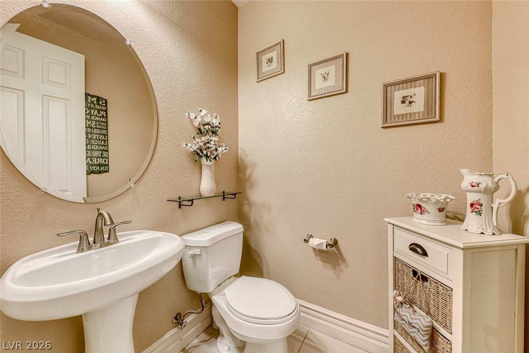 70 Portezza Drive, Henderson, NV 89011 A well-appointed powder room features a pedestal sink and warm wall tones.