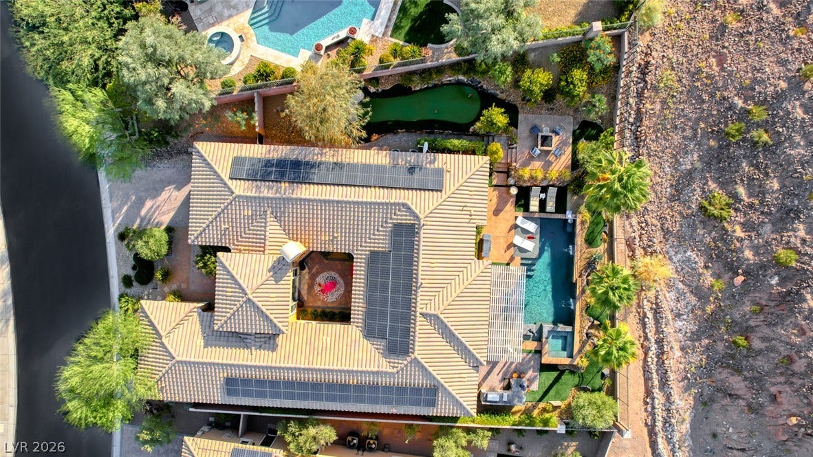 70 Portezza Drive, Henderson, NV 89011 An aerial perspective reveals a luxurious home featuring solar panels, multiple pools, and an integrated putting green.