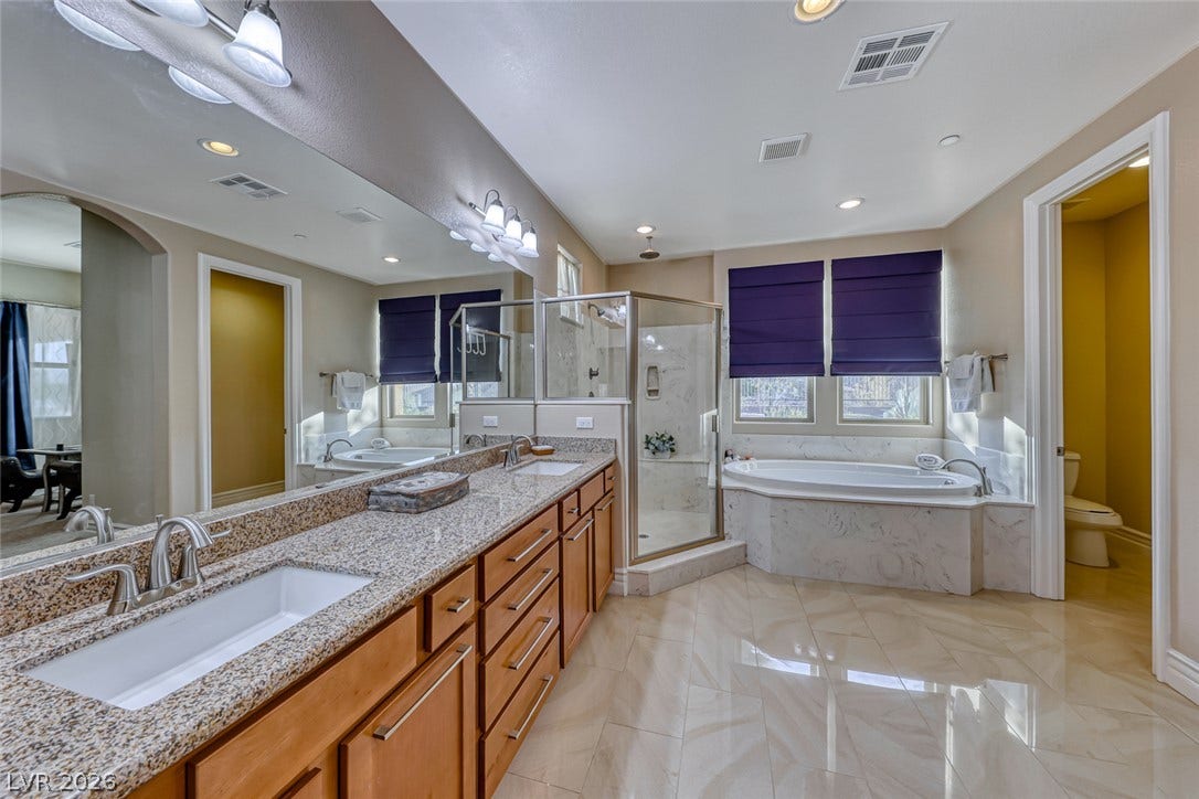 70 Portezza Drive, Henderson, NV 89011 Indulge in a luxurious primary bathroom, featuring a dual vanity, an oversized soaking tub, and a glass-enclosed shower.