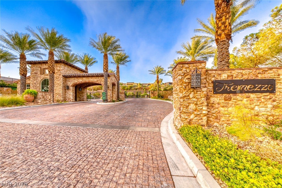 70 Portezza Drive, Henderson, NV 89011 Secure community entrance with elegant stonework and lush palm trees welcomes you home.
