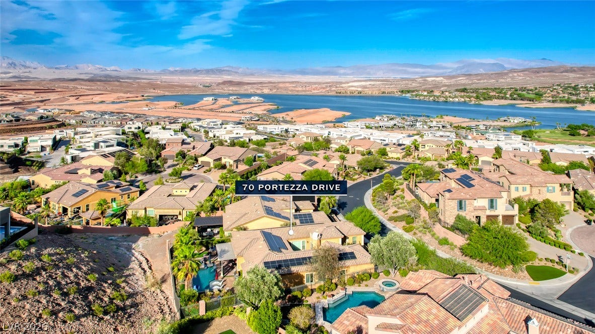 70 Portezza Drive, Henderson, NV 89011 An aerial perspective reveals a vibrant community with houses, sparkling pools, and scenic lake and mountain views.