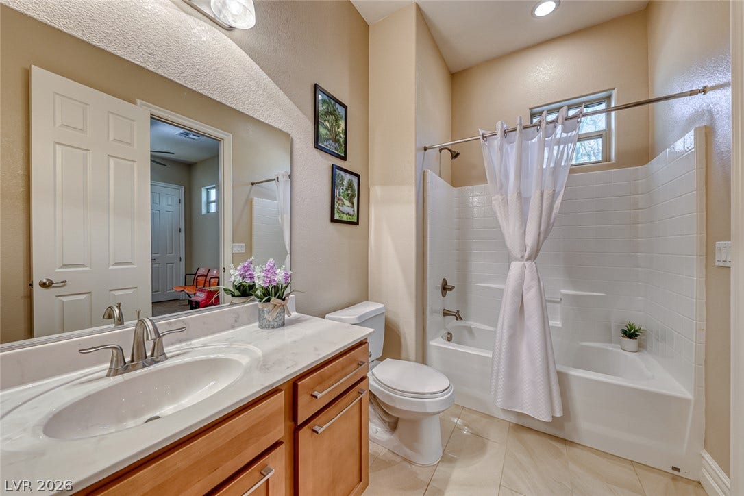 70 Portezza Drive, Henderson, NV 89011 A clean, well-appointed bathroom featuring a tub-shower combination with bright white tiling and a modern vanity.